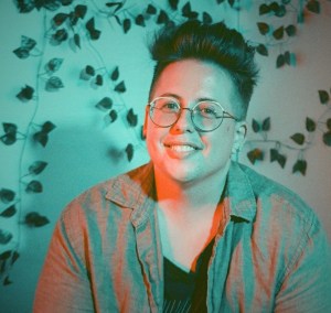 A person with short hair and glasses smiles.